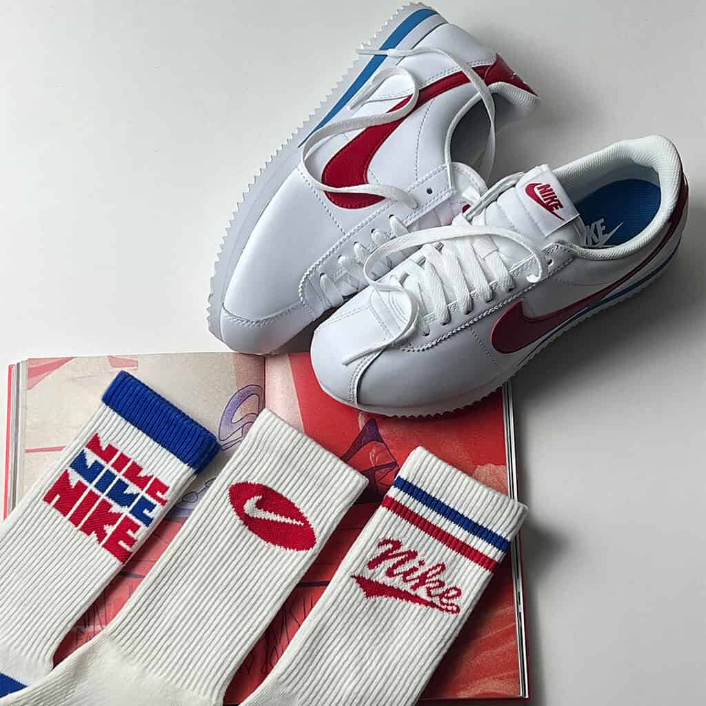 Tênis Nike Cortez branco com detalhes vermelhos e azuis.